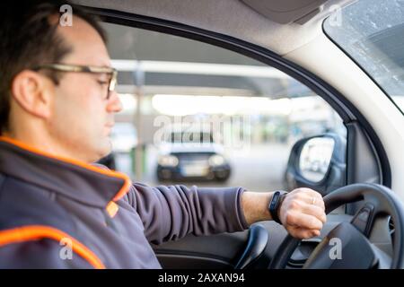 Delivery man driving a car and looking on the watch Stock Photo