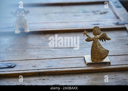 Beautiful angels on a rustic wooden piece of furniture in atmospheric mood, lense flare Stock Photo