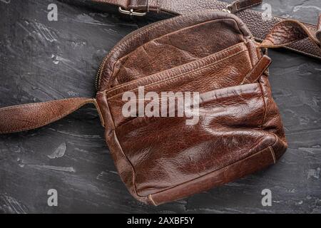 brown stylish leather old shoulder bag with a shoulder strap on a dark structural background with texture. good concept and background for the layout. Stock Photo