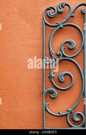 A Decorative Piece of Wrought Iron Mounted to a Bright Colored Stucco Wall Stock Photo