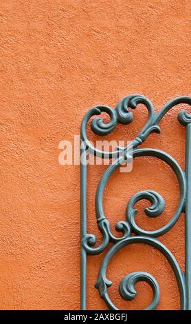 A Decorative Piece of Wrought Iron Mounted to a Bright Colored Stucco Wall Stock Photo