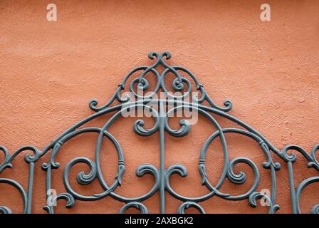 A Decorative Piece of Wrought Iron Mounted to a Bright Colored Stucco Wall Stock Photo