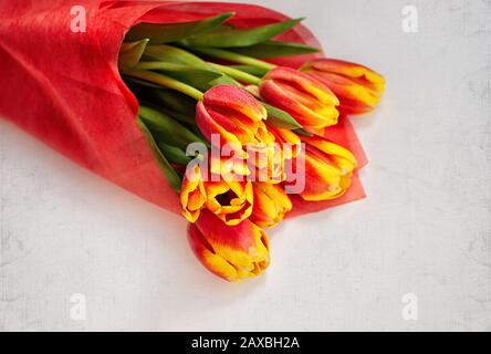 Bouquet of red tulips on a light vintage background with space for text. Spring card. Woman day concept. Close up. Stock Photo