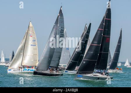 large racing yachts in the solent off of cowes during the annual cowes week regatta sailing in a race with crews in competition. Stock Photo
