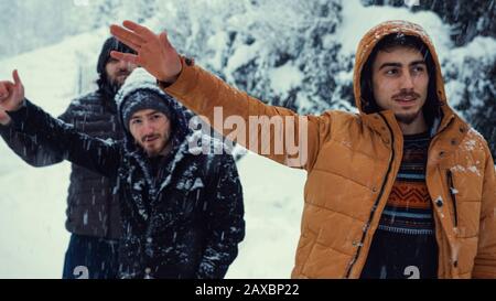 While it is snowing on a winter day, the cold men makes a hand sign to stop the bus.Transportation concept in winter. Stock Photo