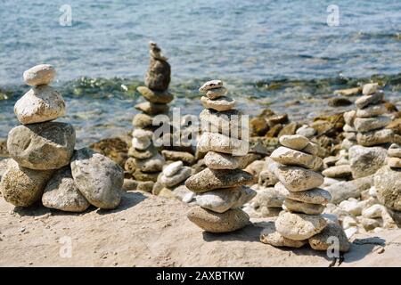 Pyramids of stones on the rocky coast of the Adriatic sea in Croatia. Against the background of sea waves. Stock Photo