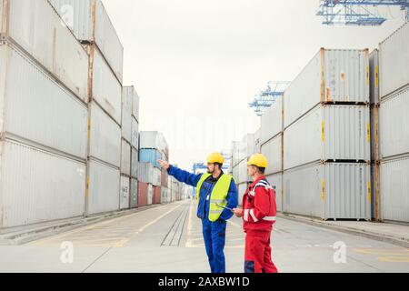Dock workers talking among cargo containers at shipyard Stock Photo