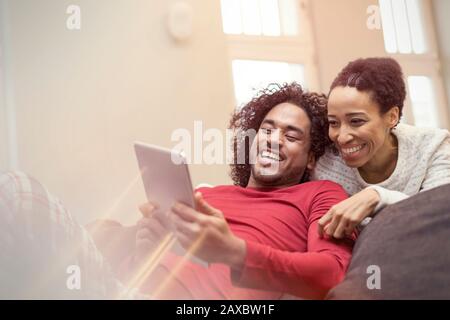 Happy couple using digital tablet on sofa Stock Photo