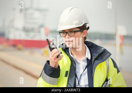 Female dock worker with walkie-talkie at shipyard Stock Photo