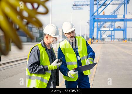 Dock workers with walkie-talkie and clipboard meeting at shipyard Stock Photo