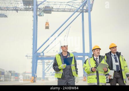 Dock workers and manager walking below crane at shipyard Stock Photo