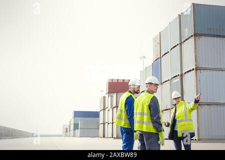 Dock workers and manager talking at cargo containers at shipyard Stock Photo