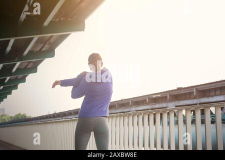 Young female runner stretching arms along urban railing Stock Photo