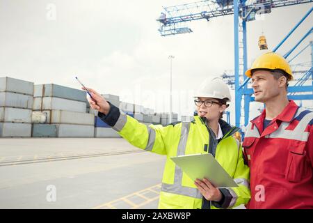 Dock workers with clipboard talking at shipyard Stock Photo
