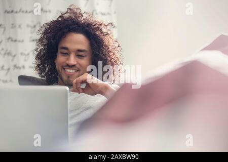 Smiling young man using laptop on sofa Stock Photo