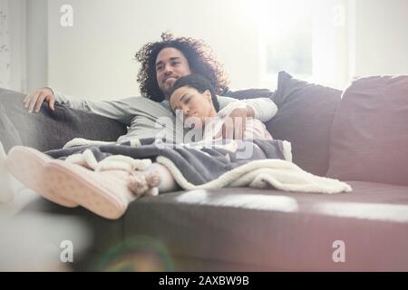Affectionate couple relaxing, watching TV on sofa
