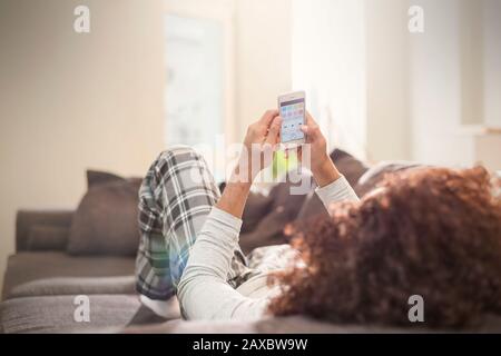 Man relaxing, using smart phone on sofa Stock Photo