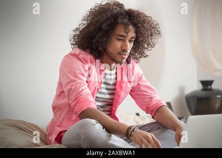 Young man working at laptop on bed Stock Photo