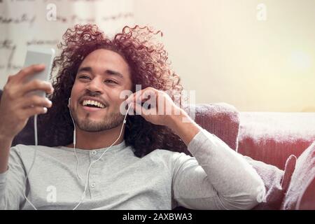 Smiling young man listening to music with headphones and mp3 player Stock Photo
