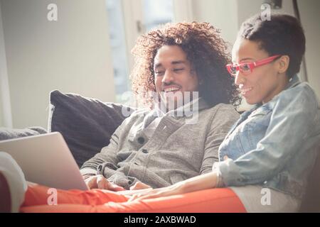 Couple relaxing, using laptop on sofa Stock Photo