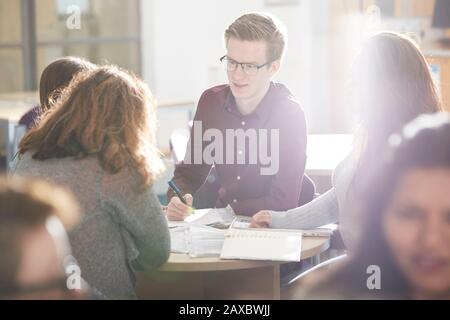 Young college students studying together in sunny classroom Stock Photo