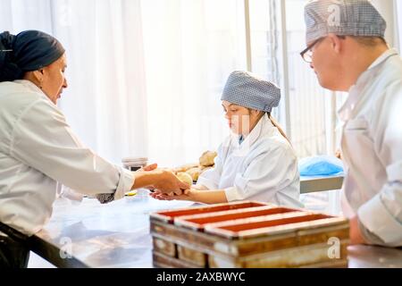 Chef helping students with Down Syndrome in baking class Stock Photo