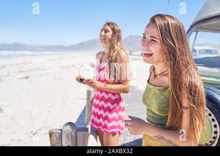Happy young women friends laughing on sunny beach Stock Photo