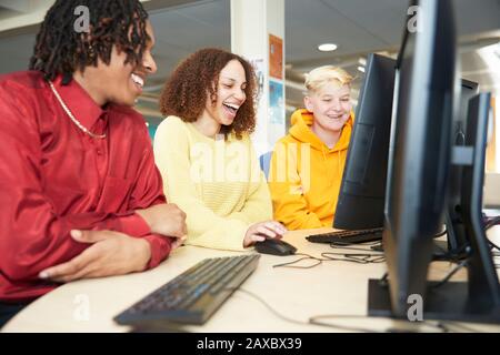 Happy college students studying together at computer in library Stock Photo