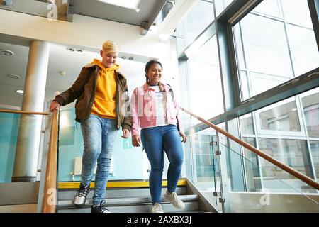 Confident young female college students descending staircase Stock Photo