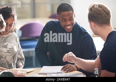 Happy young male college students studying and talking in classroom Stock Photo