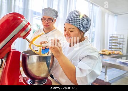 Young students with Down Syndrome using stand mixer in baking class Stock Photo