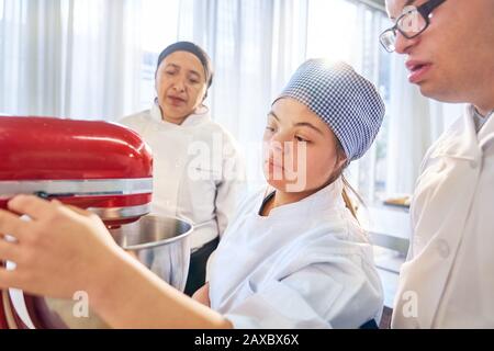 Students with Down Syndrome using stand mixer in baking class Stock Photo
