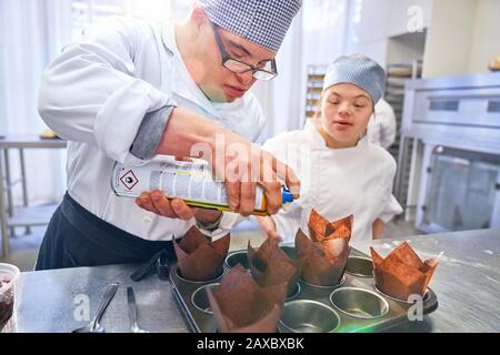 Students with Down Syndrome baking muffins in kitchen Stock Photo