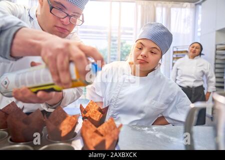 Young students with Down Syndrome baking muffins in kitchen Stock Photo