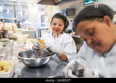Portrait confident young woman with Down Syndrome cooking in cafe Stock Photo