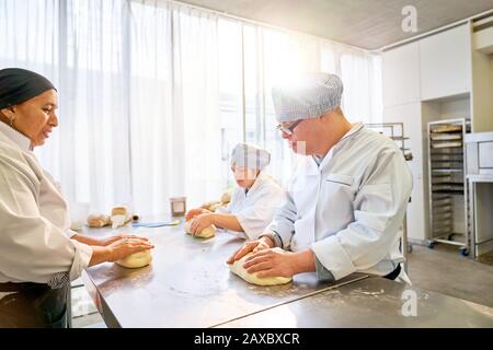 Chef teaching students with Down Syndrome how to bake in kitchen Stock Photo