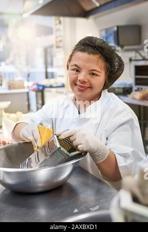 Portrait happy young woman with Down Syndrome working kitchen Stock Photo
