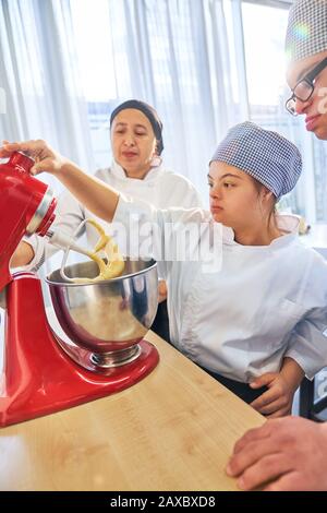 Students with Down Syndrome using stand mixer in baking class Stock Photo