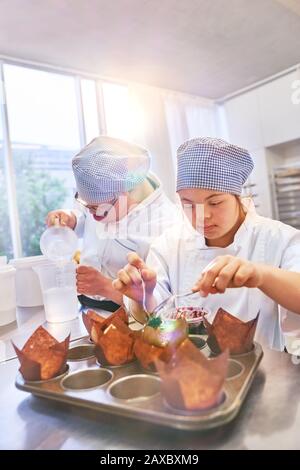 Young students with Down Syndrome baking muffins in kitchen Stock Photo