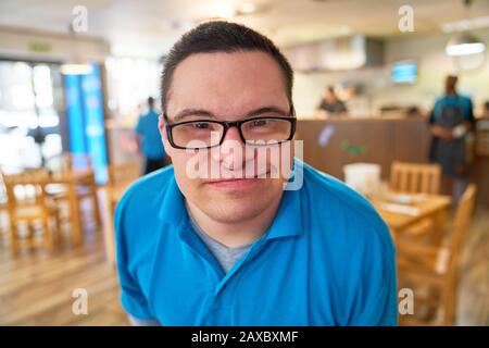 Close up portrait smiling young man with Down Syndrome in cafe Stock Photo