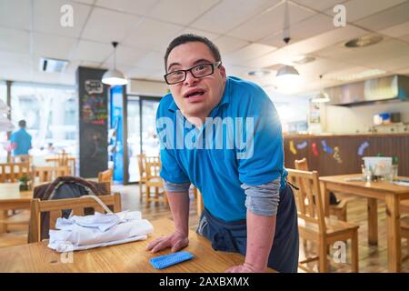 Portrait confident young man with Down Syndrome working in cafe Stock Photo