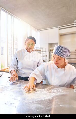 Baking instructor and young student with Down Syndrome flour surface Stock Photo