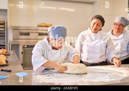 Chef teaching students with Down Syndrome how to knead dough Stock Photo