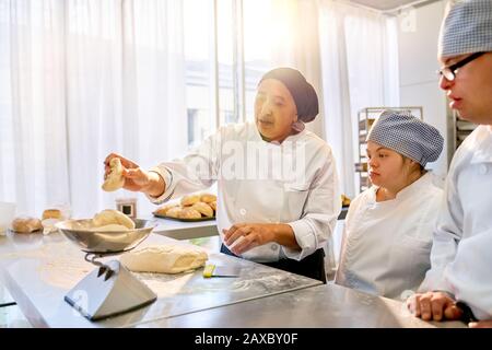 Chef teaching students with Down Syndrome how to bake Stock Photo