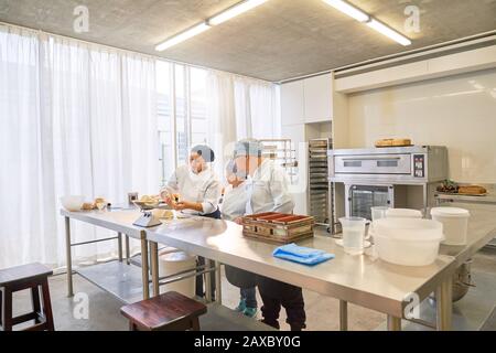 Chef and students with Down Syndrome baking in restaurant kitchen Stock Photo