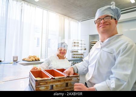 Portrait happy students with Down Syndrome baking in kitchen Stock Photo