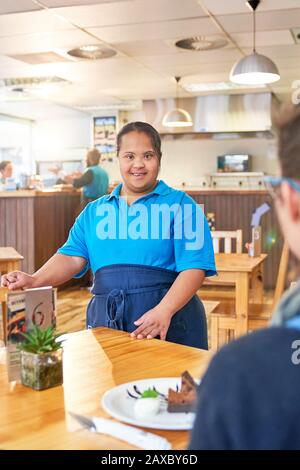 Portrait confident young female server with Down Syndrome in cafe Stock Photo