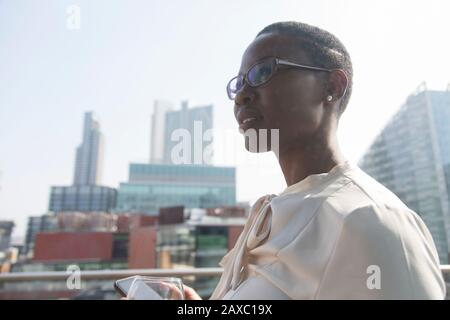 Ambitious, confident businesswoman on sunny, urban balcony Stock Photo