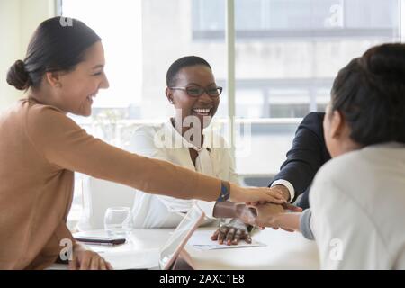 Happy business people joining hands in conference room meeting Stock Photo