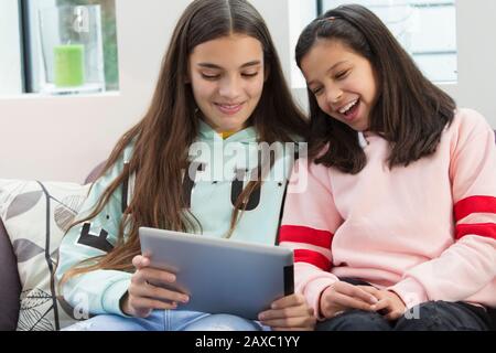 Smiling sisters using digital tablet Stock Photo